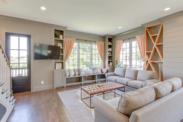 living room with hardwood / wood-style flooring, wooden walls, and ornamental molding