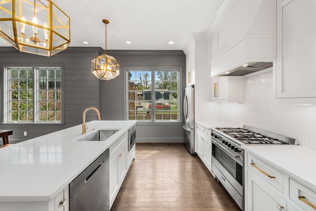 kitchen with hanging light fixtures, dark hardwood / wood-style flooring, stainless steel appliances, a kitchen island with sink, and sink