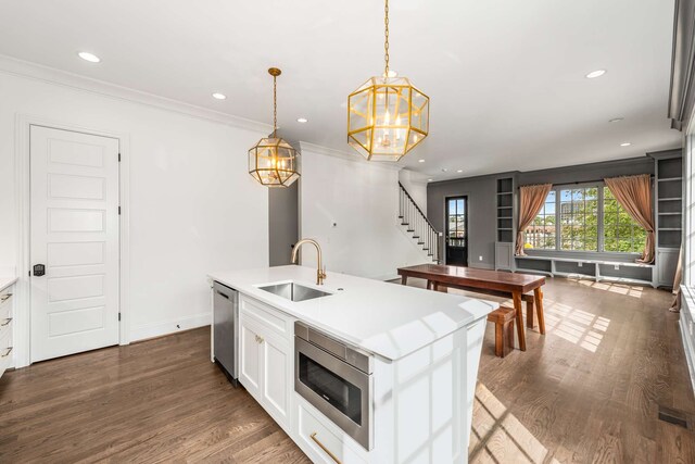 kitchen featuring sink, pendant lighting, an island with sink, and dark wood-type flooring