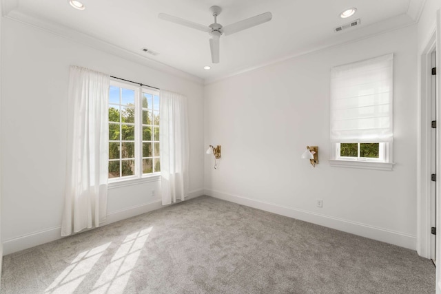 empty room featuring crown molding, ceiling fan, light colored carpet, and a wealth of natural light