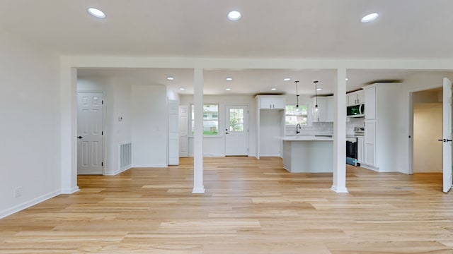 kitchen with appliances with stainless steel finishes, a kitchen island, pendant lighting, and white cabinets