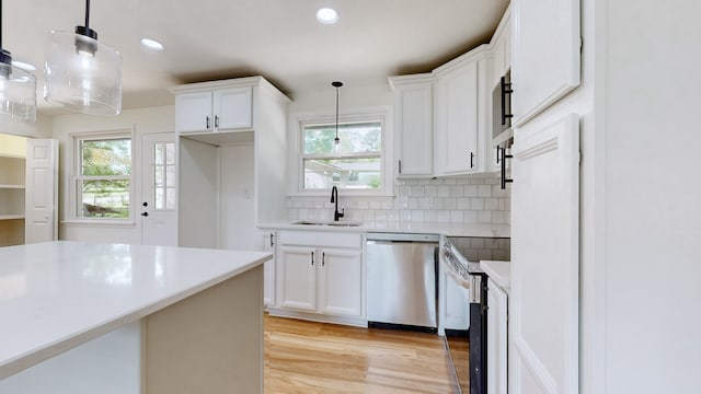 kitchen featuring appliances with stainless steel finishes, white cabinetry, sink, and decorative light fixtures