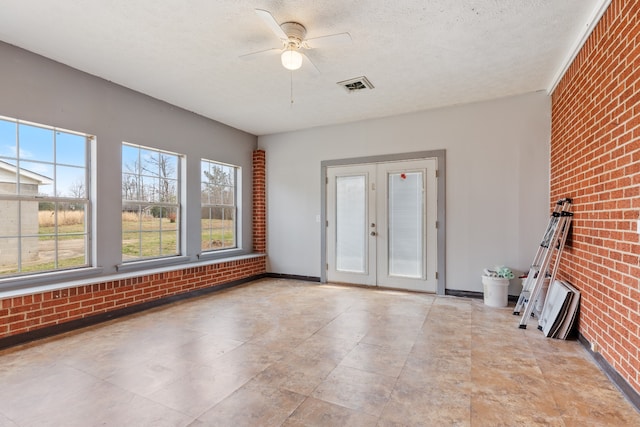 spare room featuring brick wall, a textured ceiling, french doors, and ceiling fan