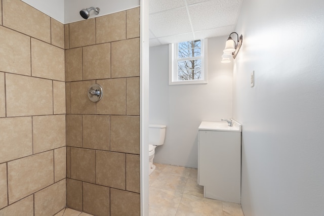 bathroom featuring a tile shower, vanity, and toilet