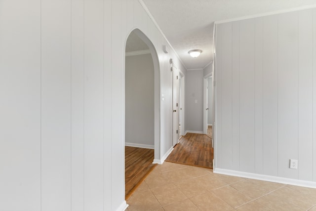 hallway featuring a textured ceiling, light hardwood / wood-style floors, and ornamental molding