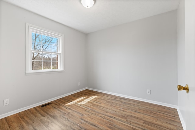 empty room with wood-type flooring and a textured ceiling