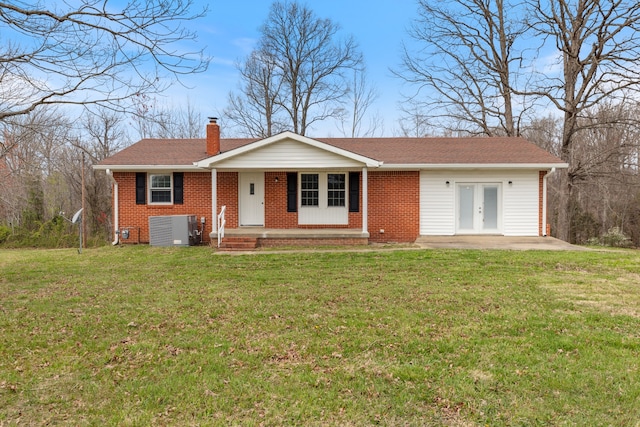 ranch-style home with a front lawn, central air condition unit, and french doors