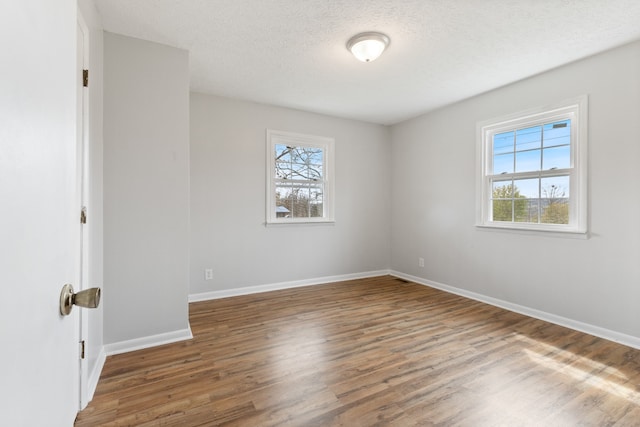 unfurnished room with wood-type flooring, a textured ceiling, and a wealth of natural light