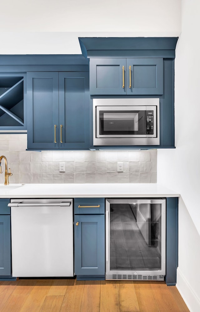 kitchen featuring wine cooler, sink, tasteful backsplash, light hardwood / wood-style flooring, and stainless steel appliances