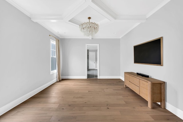 unfurnished living room featuring wood-type flooring, coffered ceiling, ornamental molding, and a chandelier