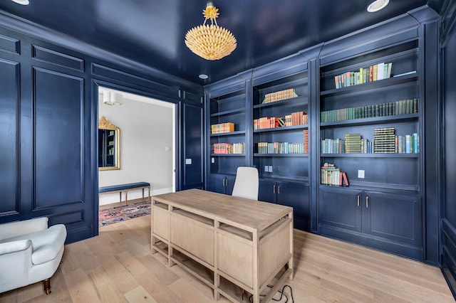 office with light hardwood / wood-style flooring and built in shelves