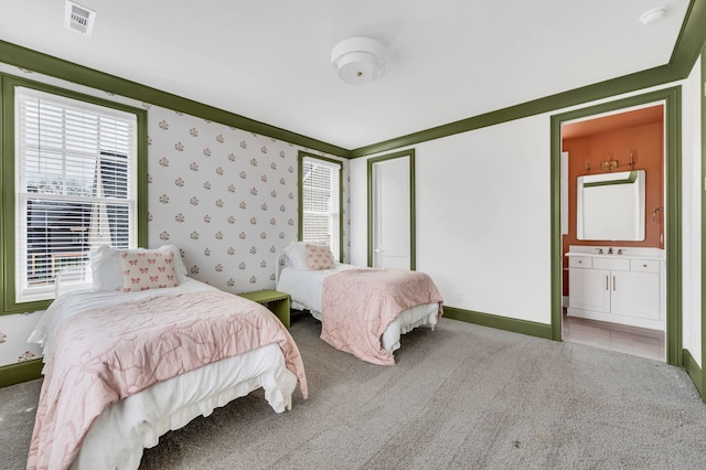 carpeted bedroom featuring connected bathroom and sink