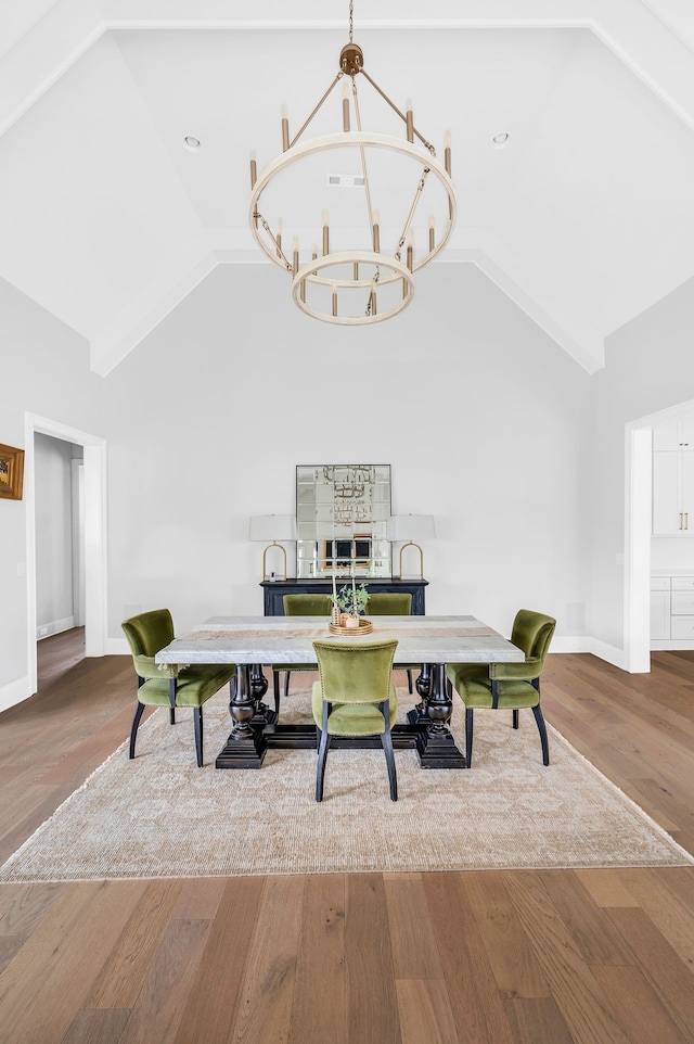 dining area featuring high vaulted ceiling, wood-type flooring, and a chandelier