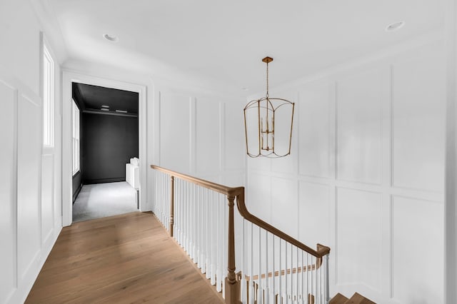 corridor with ornamental molding, hardwood / wood-style floors, and a chandelier