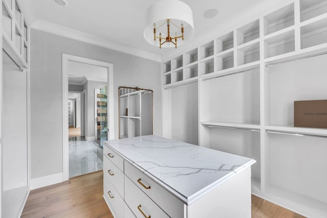 spacious closet with light hardwood / wood-style floors and a notable chandelier