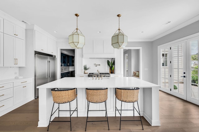 kitchen featuring wood-type flooring, pendant lighting, an island with sink, and stainless steel appliances