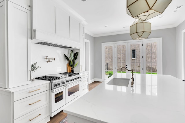 kitchen with high end white range, sink, light stone counters, and white cabinets