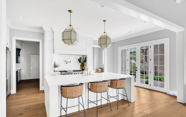 kitchen with ornamental molding, white cabinetry, light hardwood / wood-style flooring, and decorative light fixtures