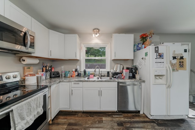 kitchen featuring appliances with stainless steel finishes, light stone counters, white cabinets, dark hardwood / wood-style floors, and sink