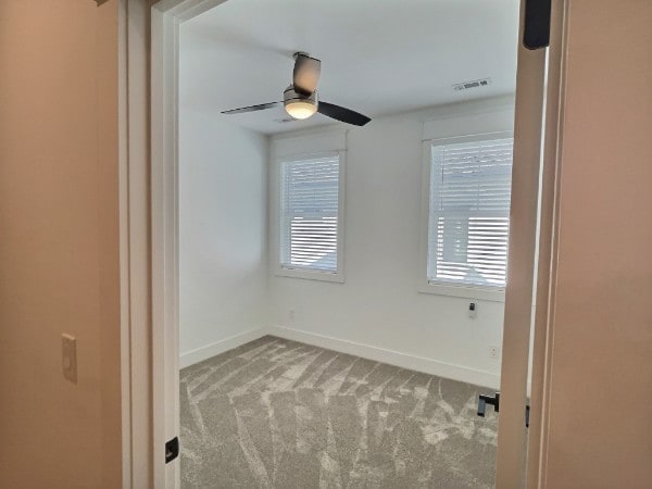 unfurnished room with ceiling fan and light colored carpet