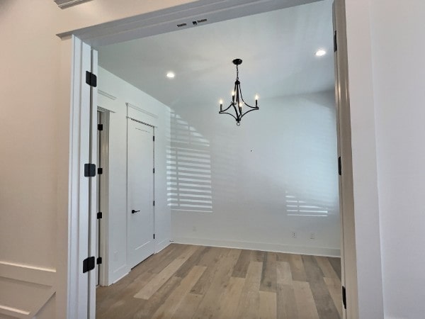 unfurnished dining area with an inviting chandelier and light hardwood / wood-style floors