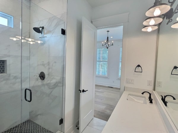 bathroom with a notable chandelier, vanity, wood-type flooring, and a shower with shower door