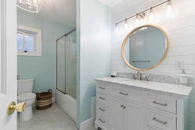 full bathroom featuring combined bath / shower with glass door, vanity, wooden walls, tile patterned flooring, and toilet