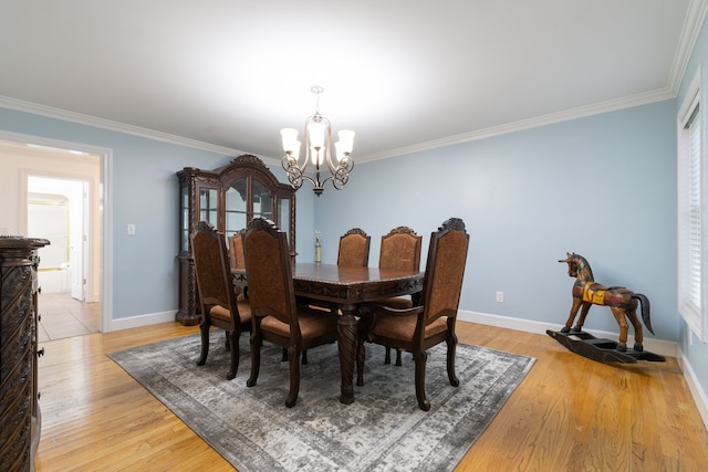 dining space featuring light hardwood / wood-style flooring, a notable chandelier, and crown molding