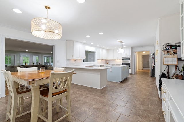 kitchen with tasteful backsplash, white cabinets, decorative light fixtures, and a kitchen island