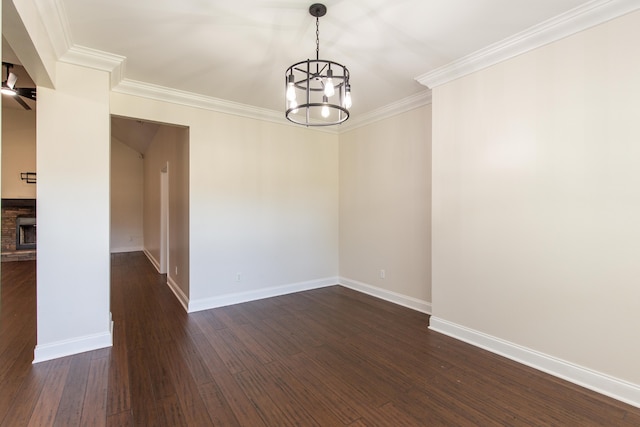 spare room with crown molding, a stone fireplace, dark hardwood / wood-style flooring, and a chandelier