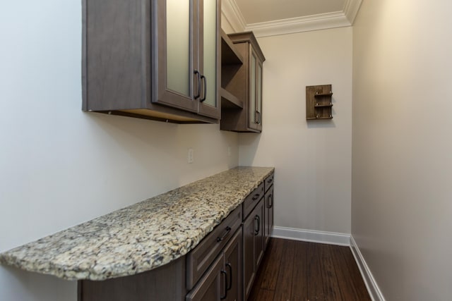 interior space with dark brown cabinets, light stone countertops, crown molding, and dark wood-type flooring