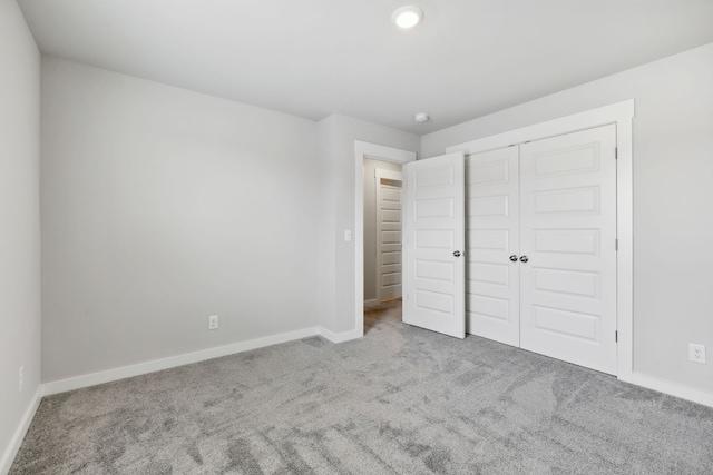 unfurnished bedroom with light carpet and a closet