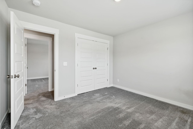 unfurnished bedroom featuring dark colored carpet and a closet