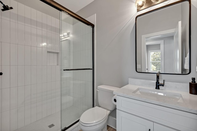 bathroom featuring toilet, vanity, and a stall shower
