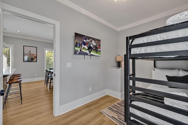 bedroom featuring baseboards, ornamental molding, and light wood-style flooring