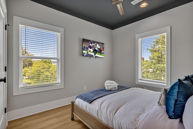 bedroom with light wood-type flooring, baseboards, recessed lighting, and multiple windows