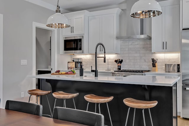 kitchen with wall chimney range hood, built in microwave, an inviting chandelier, light countertops, and backsplash