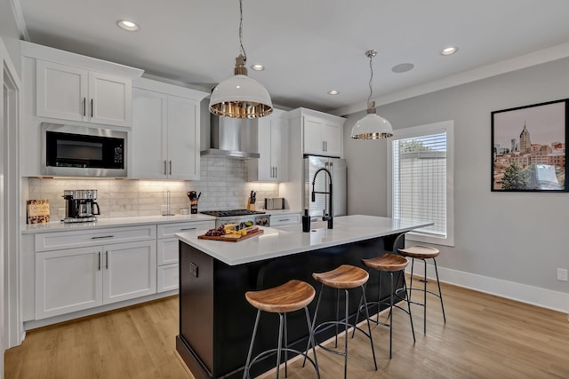 kitchen featuring wall chimney exhaust hood, built in microwave, a center island with sink, tasteful backsplash, and light countertops