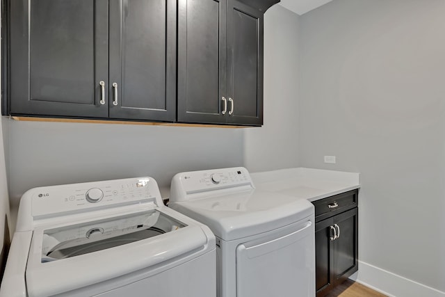 laundry area featuring separate washer and dryer, wood finished floors, baseboards, and cabinet space