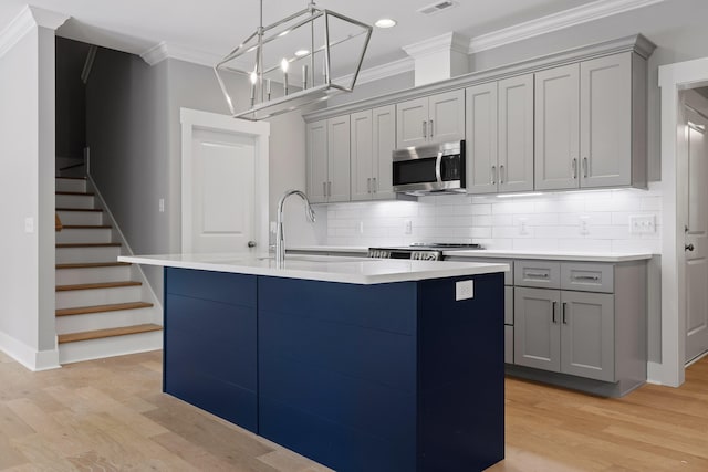 kitchen with an island with sink, gray cabinetry, and light hardwood / wood-style floors