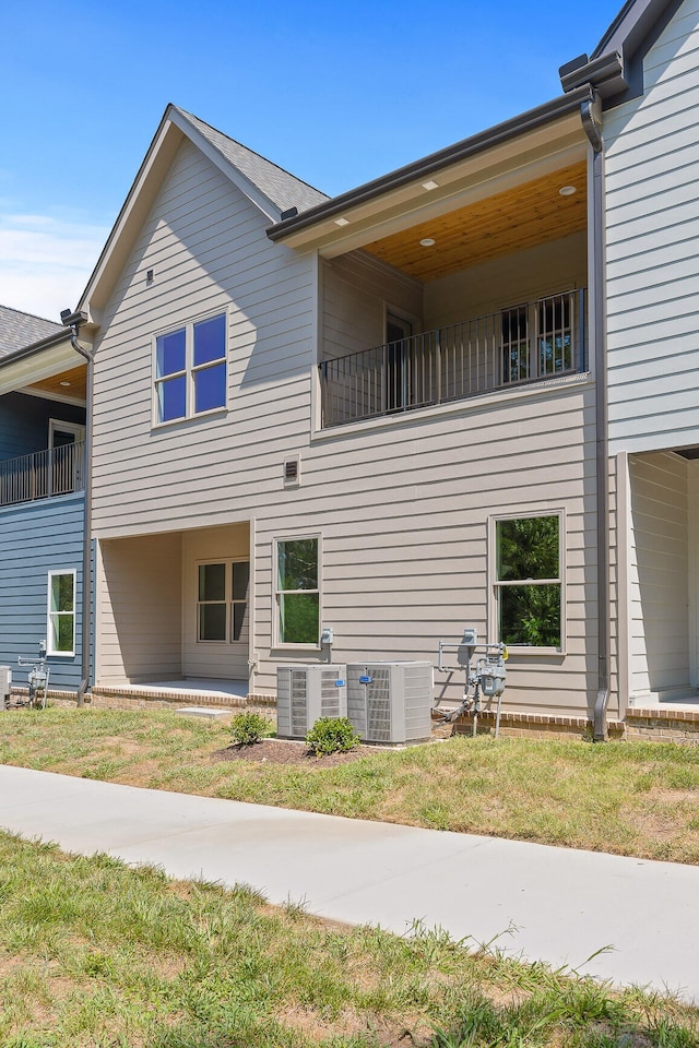 view of property exterior with a balcony, central AC, and a yard