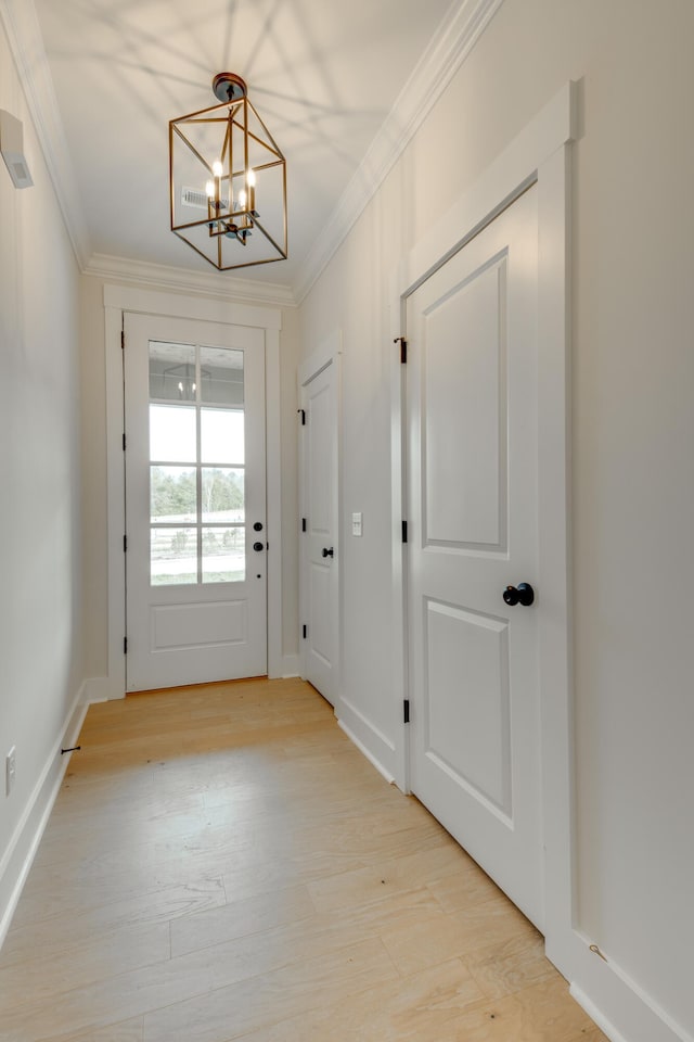 doorway to outside featuring a notable chandelier, light hardwood / wood-style flooring, and crown molding