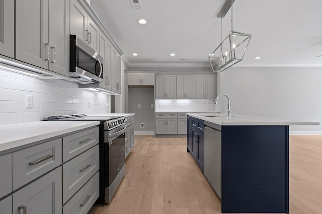 kitchen featuring sink, gray cabinetry, a kitchen island with sink, stainless steel appliances, and light wood-type flooring