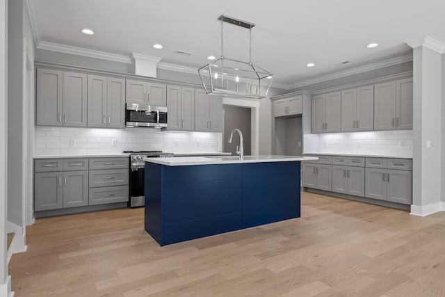 kitchen with an island with sink, stainless steel appliances, light hardwood / wood-style floors, and gray cabinetry