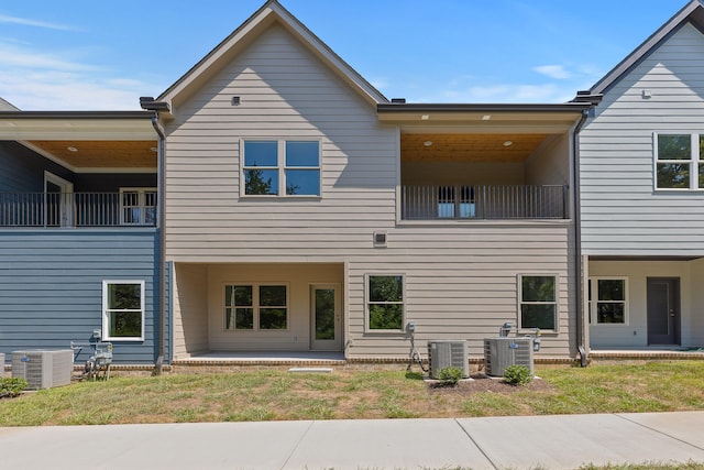 back of house featuring a balcony, central AC, and a yard