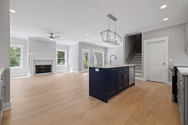 kitchen with a healthy amount of sunlight, a center island with sink, sink, and hanging light fixtures