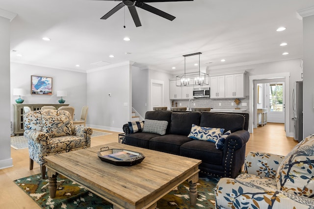 living room featuring ornamental molding, light hardwood / wood-style floors, and ceiling fan with notable chandelier