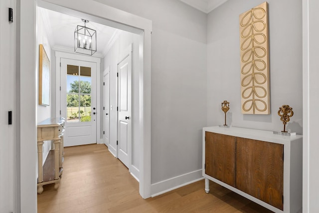 doorway featuring baseboards, wood finished floors, an inviting chandelier, and ornamental molding