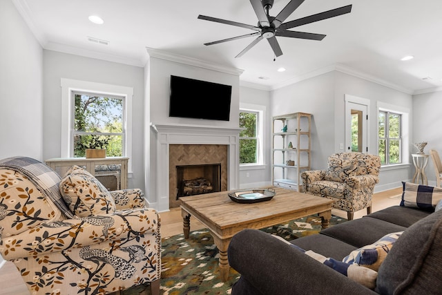 living room featuring ceiling fan, crown molding, hardwood / wood-style floors, and a tile fireplace