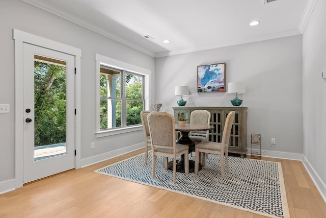 dining room with light wood finished floors, baseboards, visible vents, and crown molding